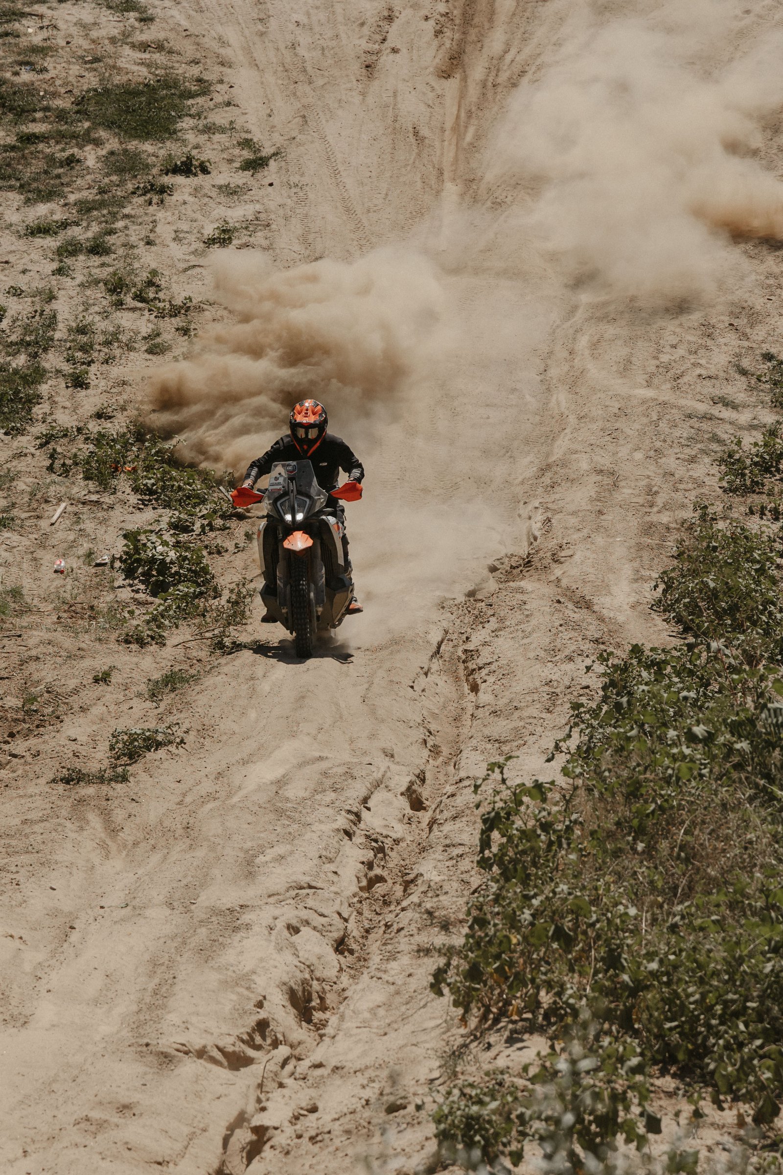 KTM throwing a dust explosion through a sandy rut