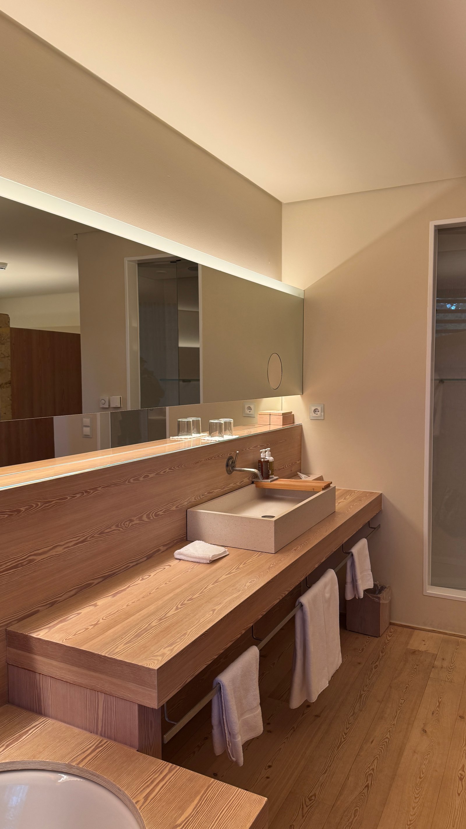 Vigilius Mountain Resort bathroom wooden vanity with stone sink and backlit mirror
